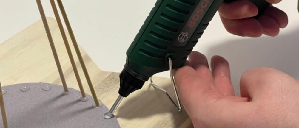 Bosch PKP 18 E Heißklebepistole beim Kleben auf Holzoberfläche im DIY-Test mit vertikalen Holzstäbchen