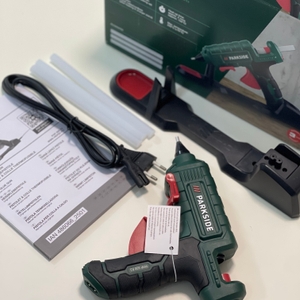 Parkside Heißklebepistole mit Zubehör, Ladestation und Anleitung im Lieferumfang auf einem Tisch