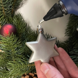 Steinel Gluematic 3002 trägt Heißkleber auf eine Weihnachtsbaum-Dekoration in Sternform auf