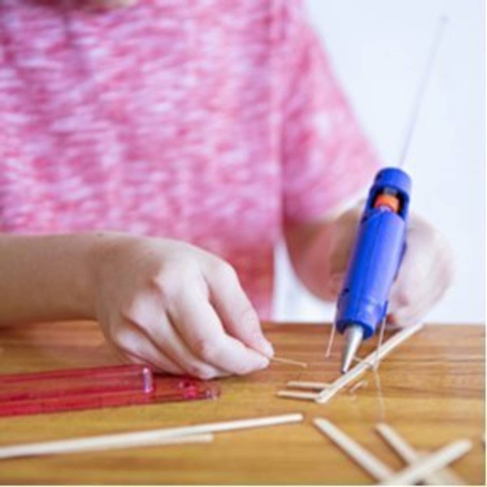 kind arbeitet mit heissklebepistole