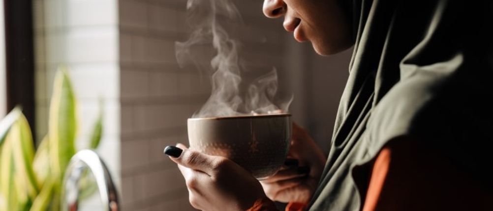 Eine Frau hält eine dampfende Tasse in der Hand.