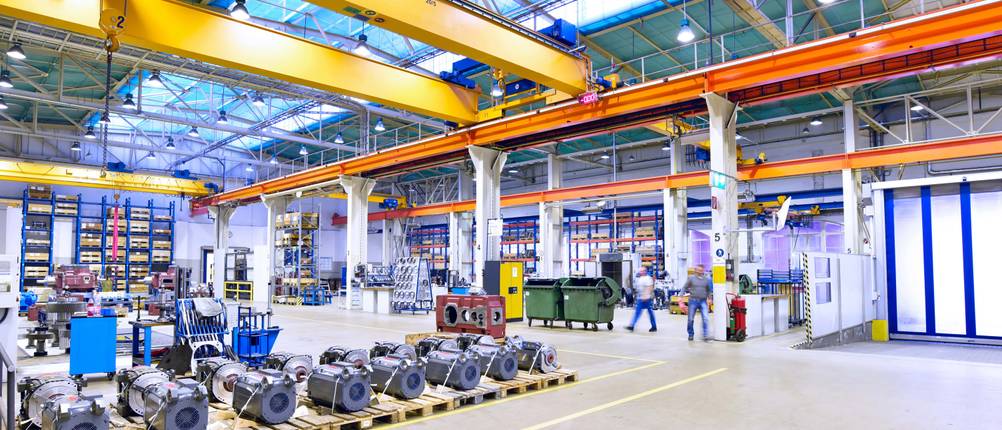Heizkanone im Test: Eine moderne Werkshalle mit Kränen und klar abgetrennten Bereichen. Im Vordergrund Paletten mit Werkstücken darauf.