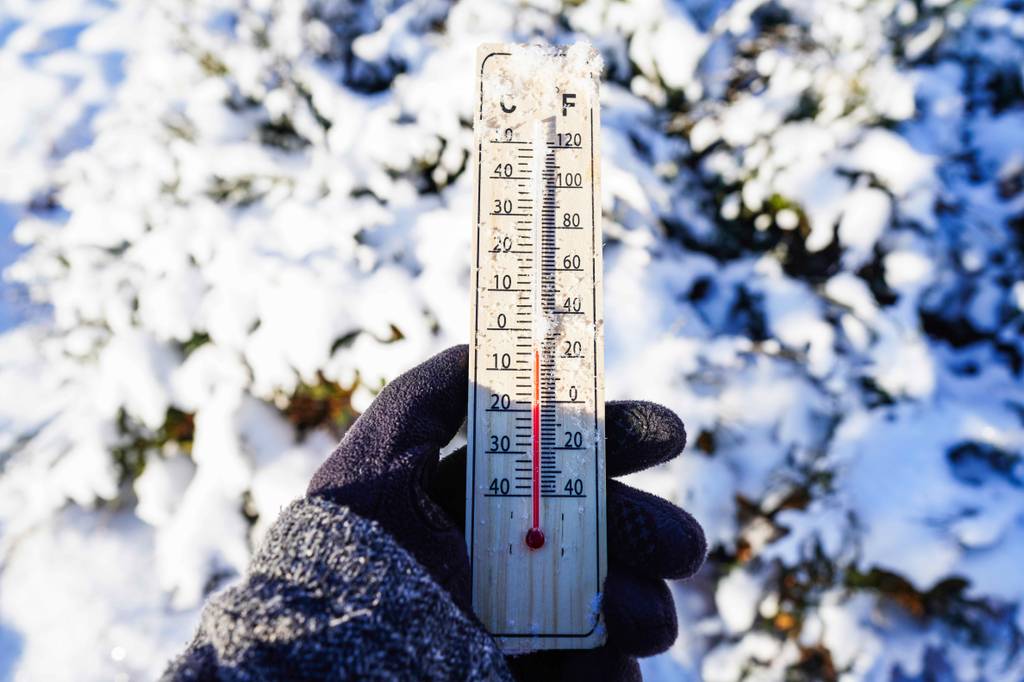 Heizkanone im Test: Ein Thermometer in einer behandschuhten Hand bei Schnee im Hintergrund und auf dem Gerät.