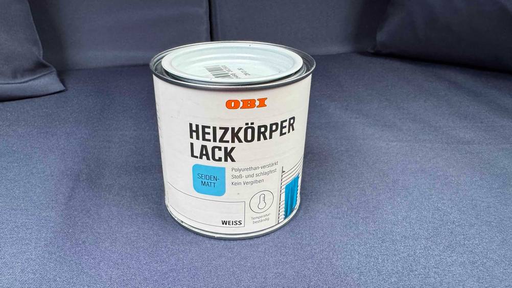 Eine Dose des getesteten Heizkörperlacks auf einem blauen Polster.