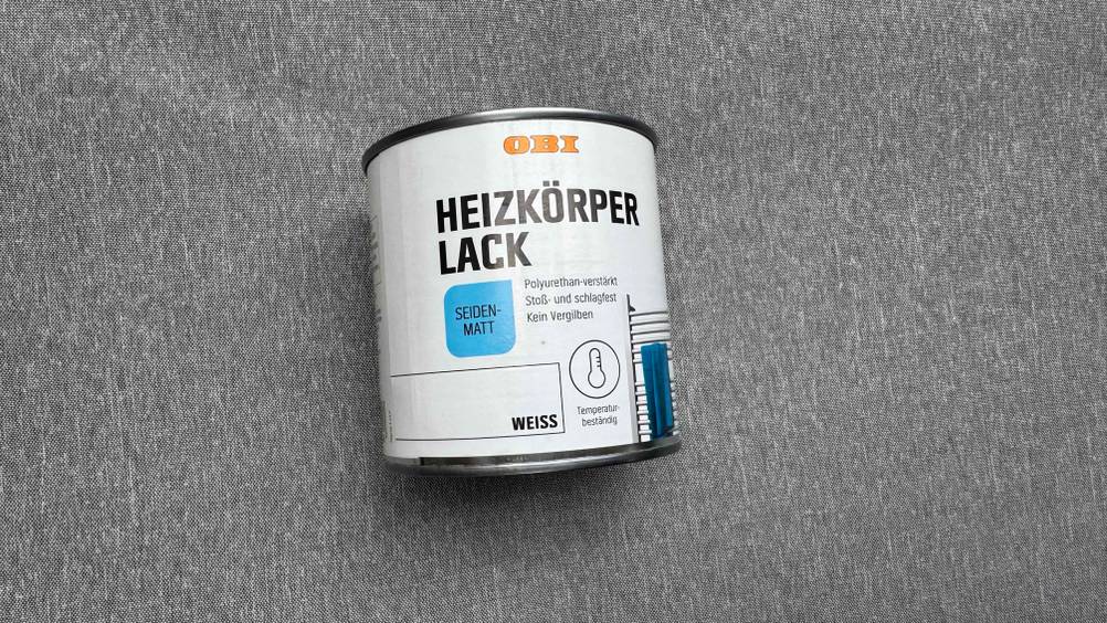 Auf einem grauen Stoff liegt ein Heizkörperlack im Test.