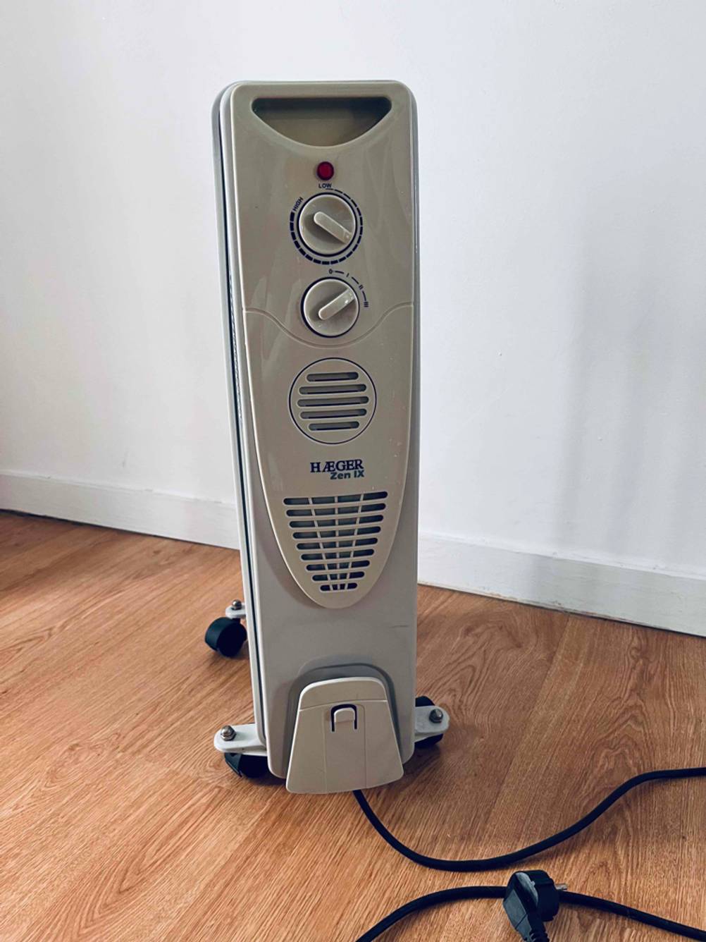 Eine getestete Heizung von vorne mit Bedienelementen auf einem Holzboden.