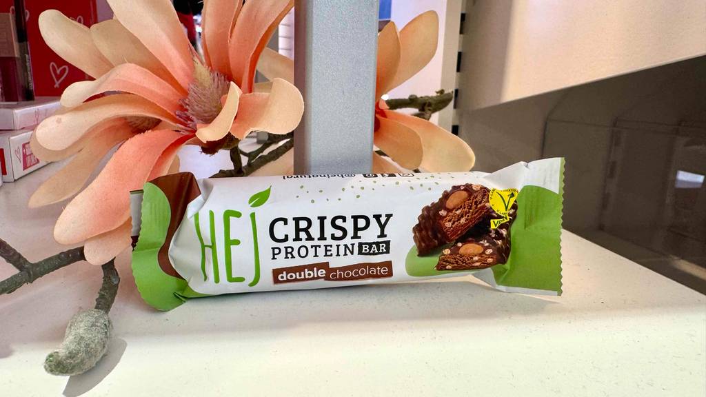 Ein getesteter vegane Proteinriegel seht vor einer Blume.