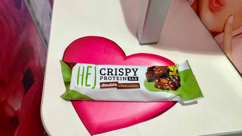Ein vegane Proteinriegel liegt zum testen auf einem rosa Herz.