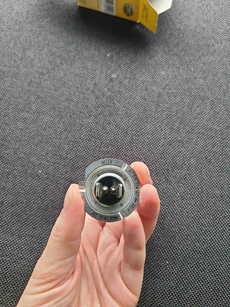 Eine Hand hält den unteren Teil der Fassung einer H7-Birne im Test in die Kamera.