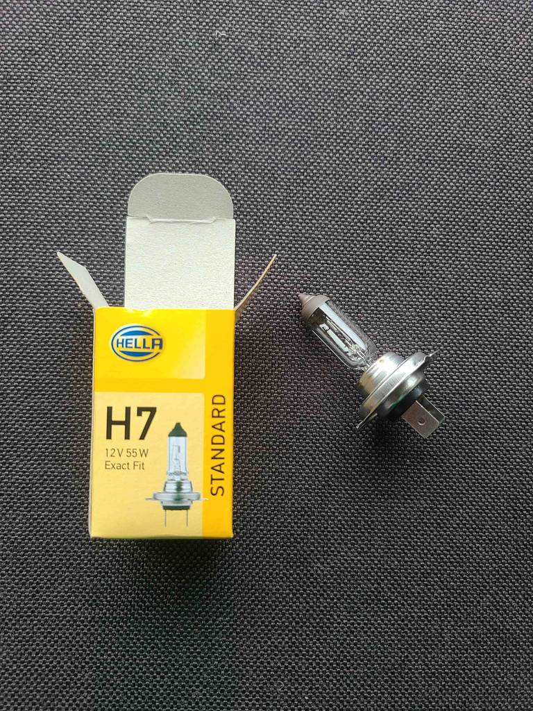 Eine geöffnete, gelbe Schachtel liegt neben der H7-Birne im Test.