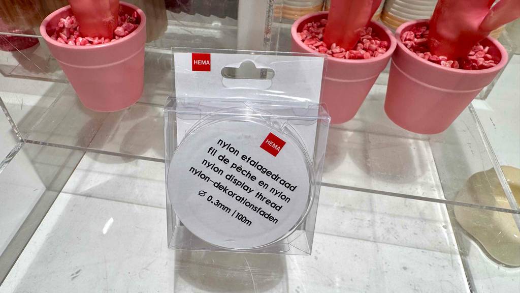 Getestet: Eine verpackte Rolle Nylonfaden steht vor mehreren rosa Deko-Blumentöpfen.