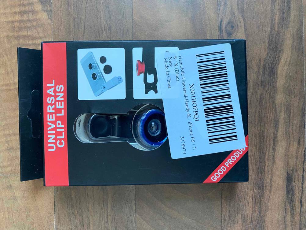 Die Originalverpackung von vorne, eines getesteten Fisheye-Objektivs auf einer Holzfläche.