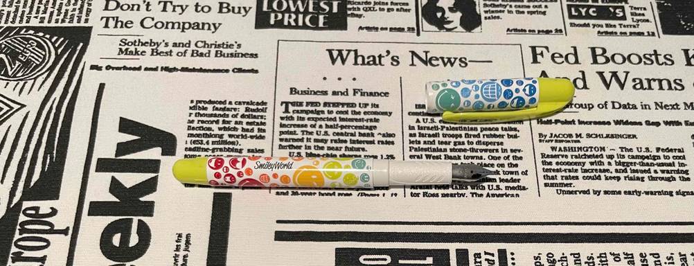 Bunter Smiley World Füller im Test liegt geöffnet auf einem Zeitungsausschnitt.