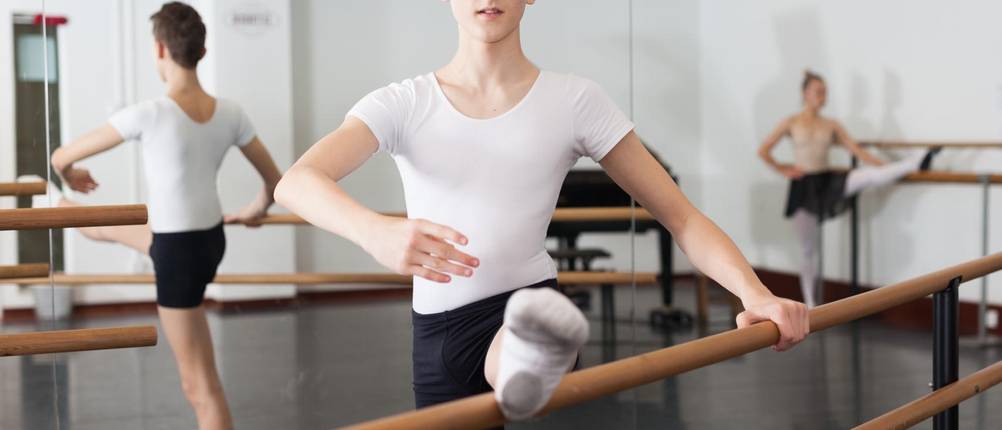 Suspensorium-Herren-Test: Ein junger Balletttänzer steht an der Ballettstange und trainiert.