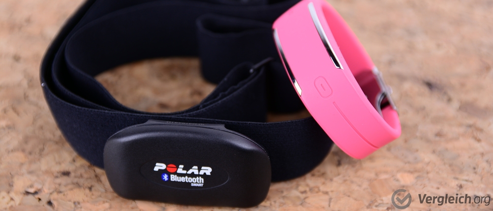 Fitness-Armband-Test: Brustgurt neben einem Fitnessarmband auf Korkuntergrund.