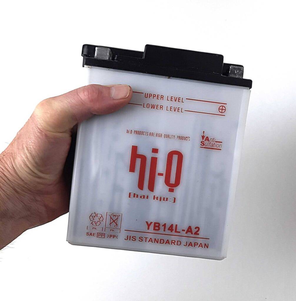 Eine Hand hält die getestete Motorrad-Batterie mit 12 V und 14 Ah vor einem weißen Hintergrund.