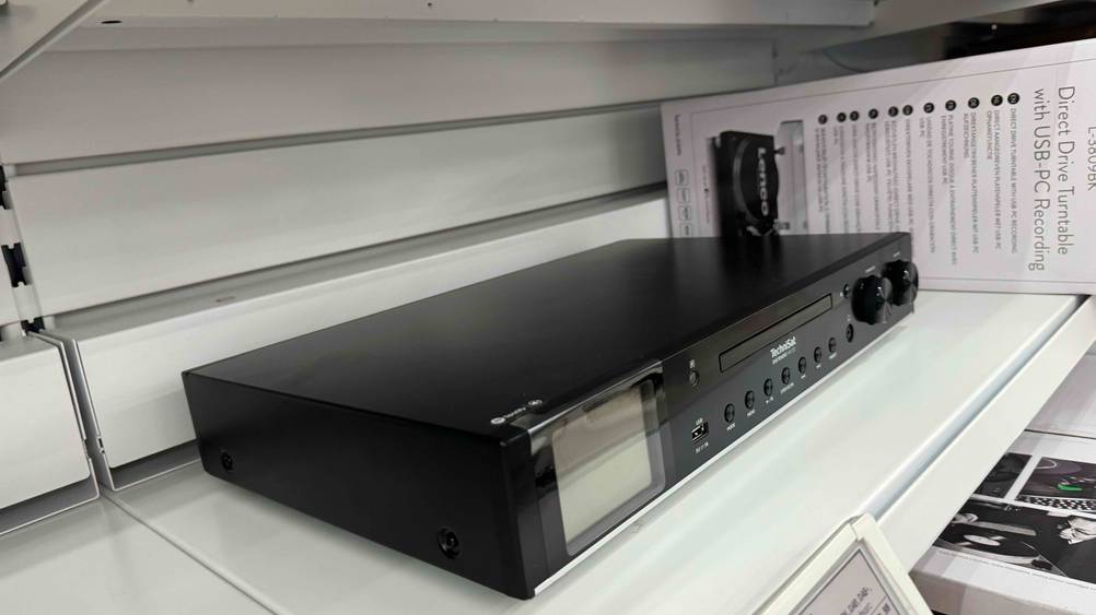Ein getesteter HiFi-Tuner von schräg seitlich in einem Verkaufsregal neben anderen Produkten.