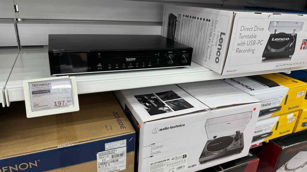 Getestet: Ein HiFi-Tuner steht in einem Verkaufsregal mit Preisschild und anderen Produkten.