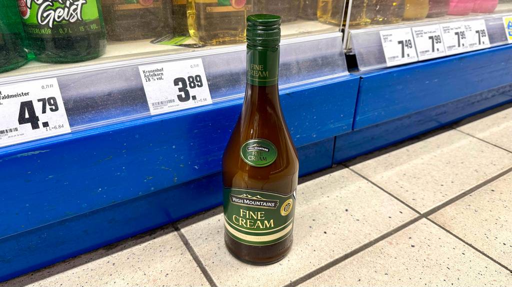 Eine Flasche Sahnelikör im Test steht vor einem Verkaufsregal inklusive Preisschildern.