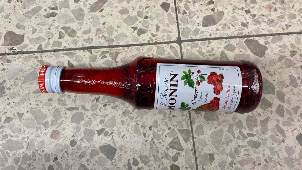 Eine Flasche getesteter Himbeersirup liegt auf dem Boden. 