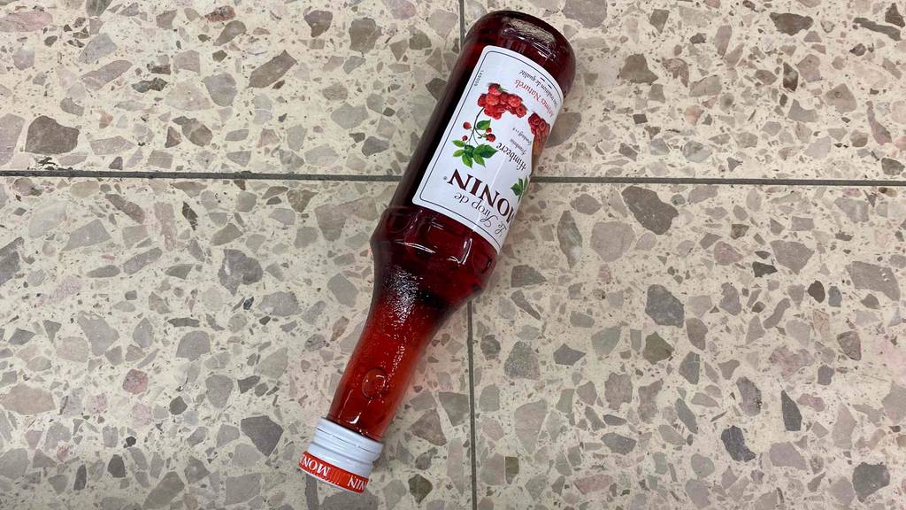 Eine Flasche getesteter Himbeersirup liegt auf dem Boden. 