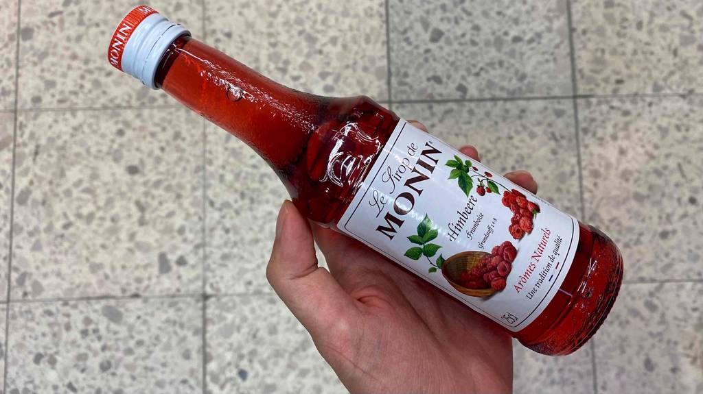 Eine Flasche getesteter Himbeersirup liegt in der Hand. 