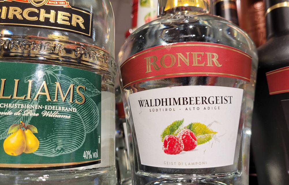 Nahaufnahme des Labels einer Flasche des getesteten Himbeergeistes neben anderen Produkten im Regal.