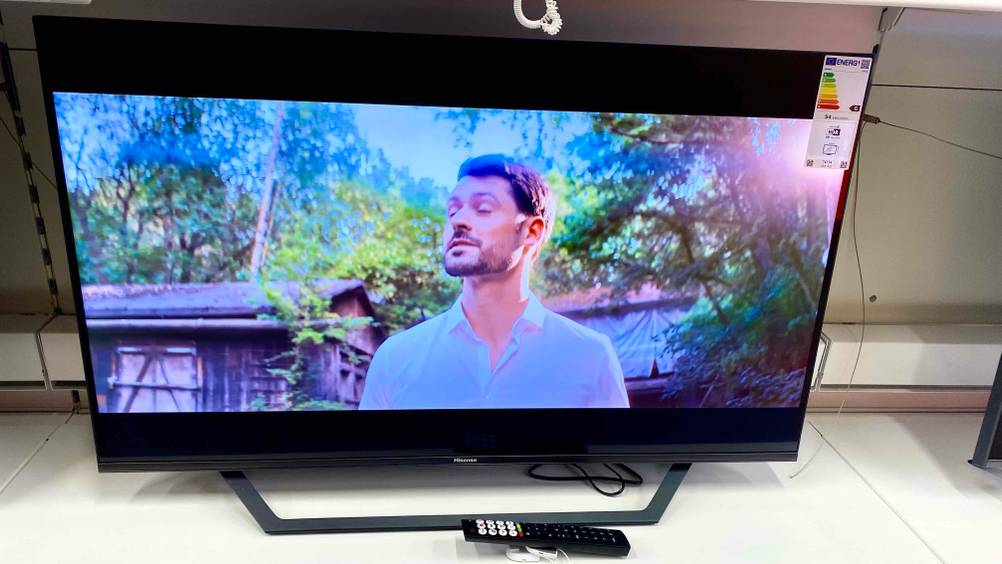 Ein 43-Zoll-Fernseher steht auf einer hellen Fläche, davor liegt die Fernbedienung.