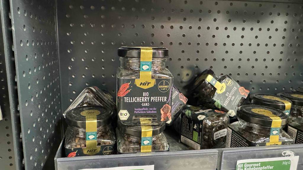 Ein getesteter Tellicherry-Pfeffer in der Kunststoffdose steht neben weiteren Pfeffersorten auf einem Regal.
