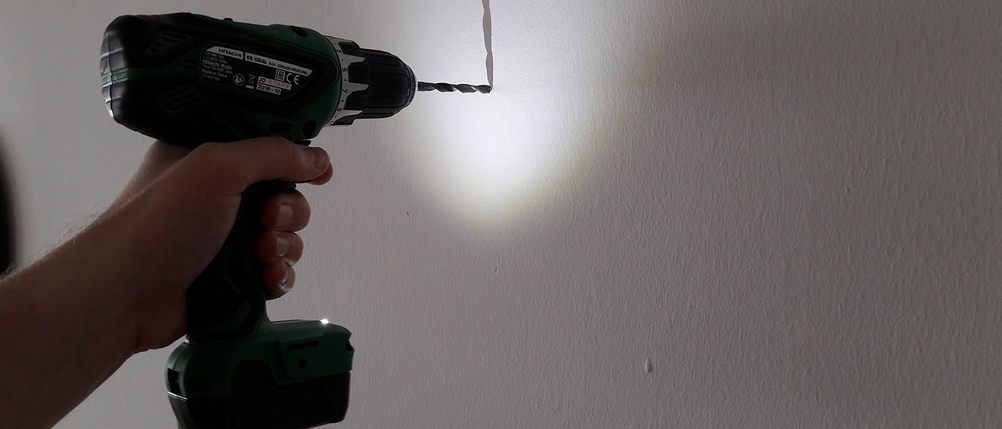 Der Hitachi Akku-Bohrschrauber 12V LED bohr ein Loch in die Wand.