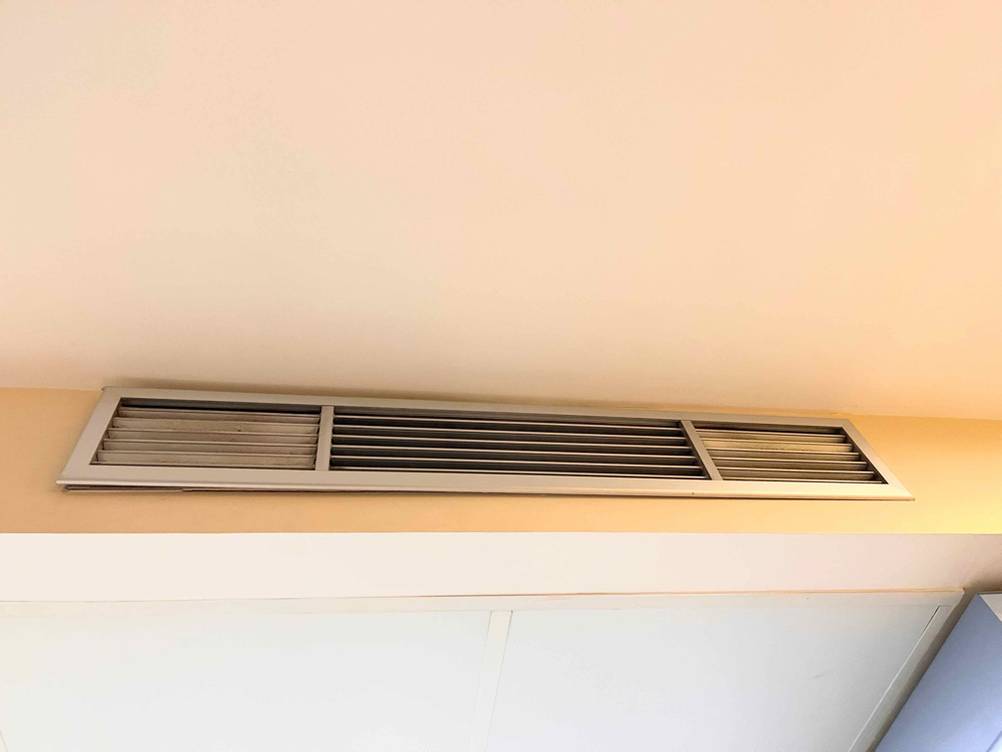 Mobile Split-Klimaanlage im Test: Ansicht einer integrierten Split-Öffnung aus Aluminium in weißen Holzunterbau.