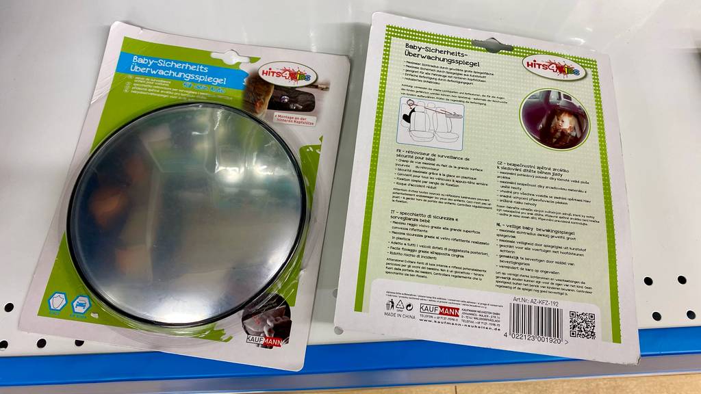 Ein runder Baby-Rückspiegel im Test befindet sich eingeschweißt in seiner Verpackung neben einer anderen Verpackung mit rückseitiger Produktbeschreibung.