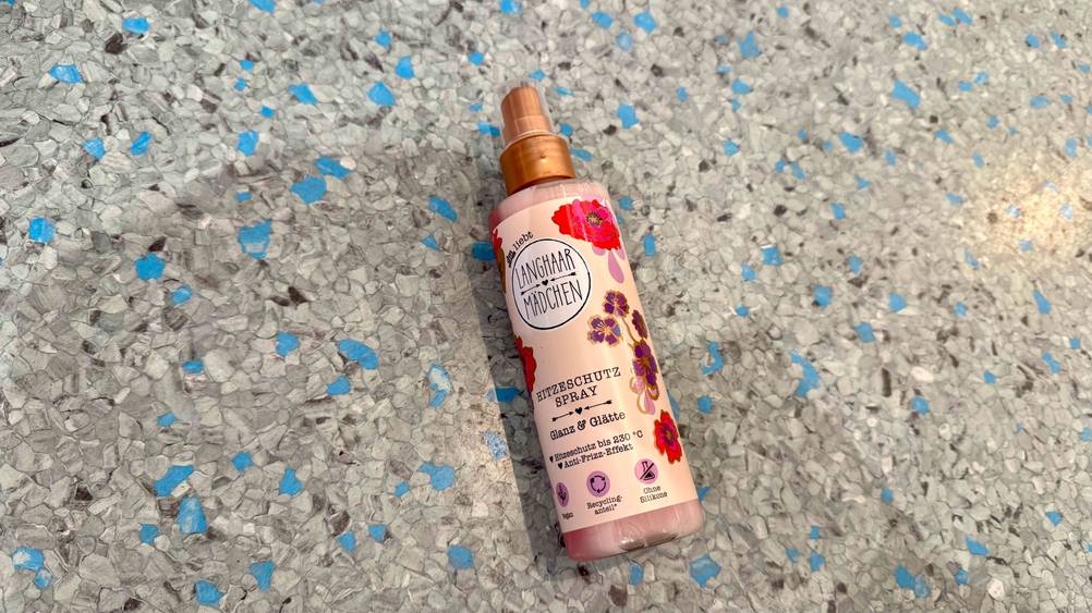Auf einem grau-blauen Boden liegt ein Hitzeschutzspray im Test.
