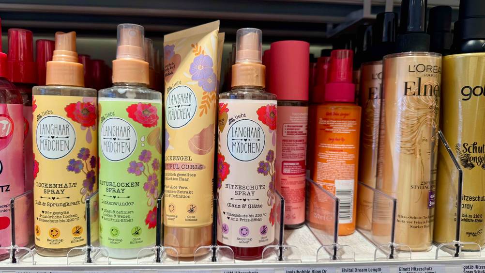 Getestet: Mehrere Hitzeschutzsprays in einem Verkaufsregal neben anderen Produkten.