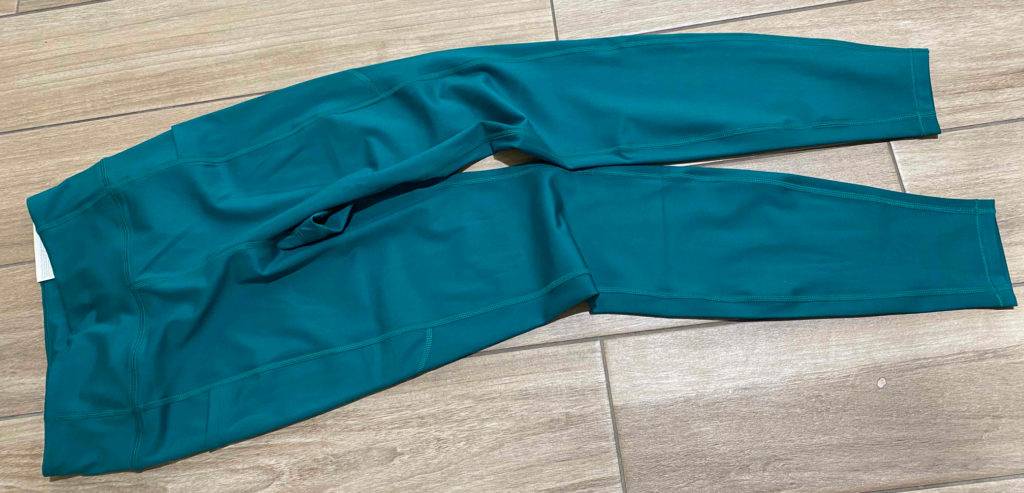 Gesamtansicht von türkisfarbigen Leggings im Test auf einem Holzboden.