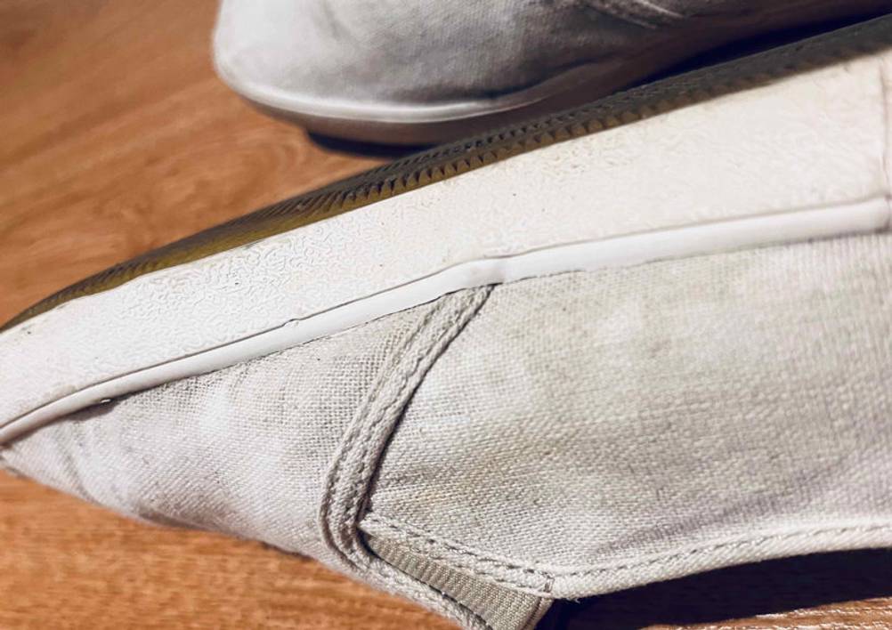 Beigefarbige Espadrilles für Herren im Test befinden sich mit Blick auf die Gummisohle auf einer Holzfläche.