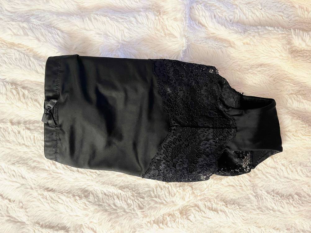 Shapewear für Damen im Test: Eine schwarze Hose mit Rüschen liegt auf weißer flauschiger Decke.