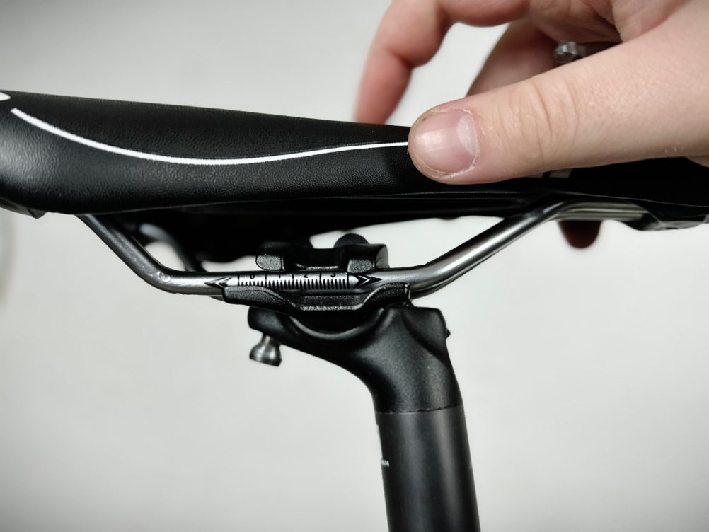 Ein Finger drückt auf den HNVNER-Fahrradsattel, um die Position oder Neigung zu prüfen. Der Montagebereich ist gut sichtbar.