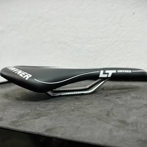 Der HNVNER-Fahrradsattel ist in der Seitenansicht zu sehen. Der Übergang von Polsterung zu Streben ist gut sichtbar.