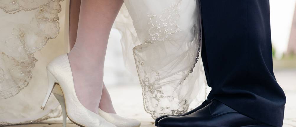 Hochzeitsschuhe-Test: Braut in weißen Pumps und Bräutigam in schwarzen Schuhen.