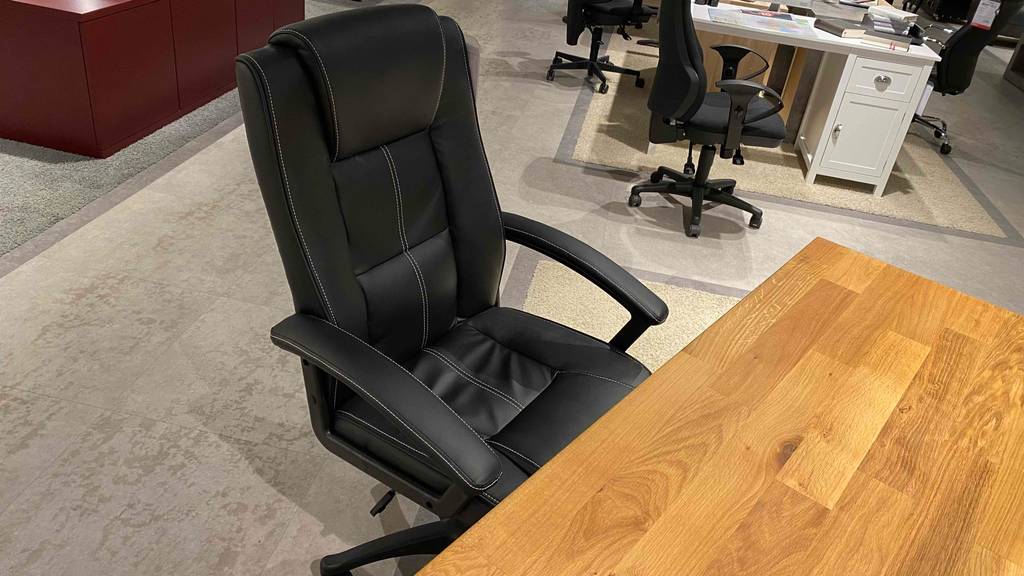 Ansicht von oben auf einen im Geschäft ausgestellten schwarzen 150-kg-Bürostuhl im Test, mit Fokus auf die gepolsterte Kopfstütze.