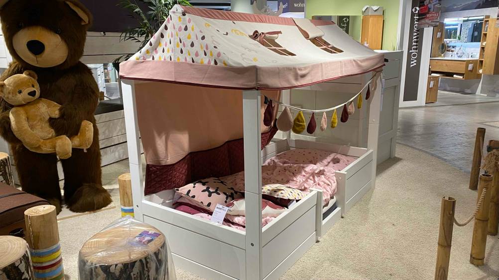 Ein getestetes Hausbett in einer Ausstellungfläche von schräg seitlich mit Preisschild.