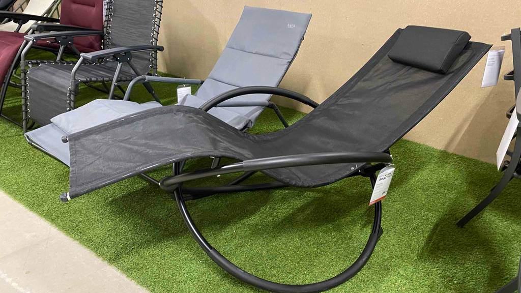 Getestet: Schaukelliegen in Schwarz und Hellgrau mit schwarzem und metallfarbenem Gestellen sowie wasserabweisenden Bezügen befinden sich auf einem Kunstrasen im Verkaufsbereich neben weiteren Outdoor-Sitzgelegenheiten.