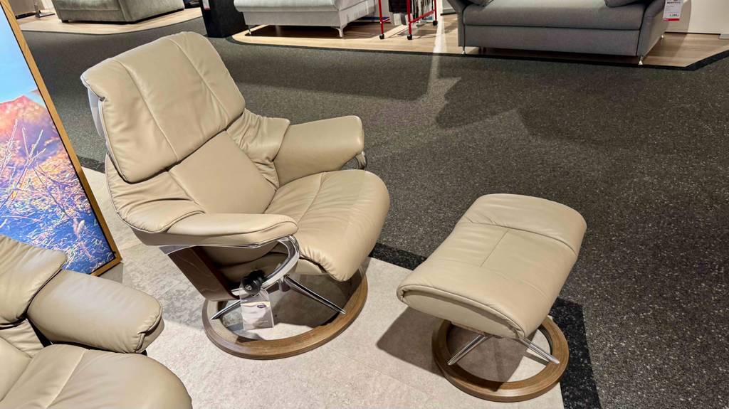 Seitliche Ansicht auf einen getesteten Relaxsessel mit Hocker in beigefarbenem Lederdesign.