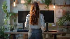 Eine Frau steht an einem Tisch mit zwei Monitoren.