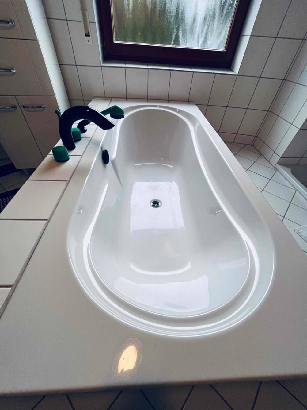 Getestete Hoesch Design Duschbadewanne befindet sich in einem weiß gefliesten Badezimmer.