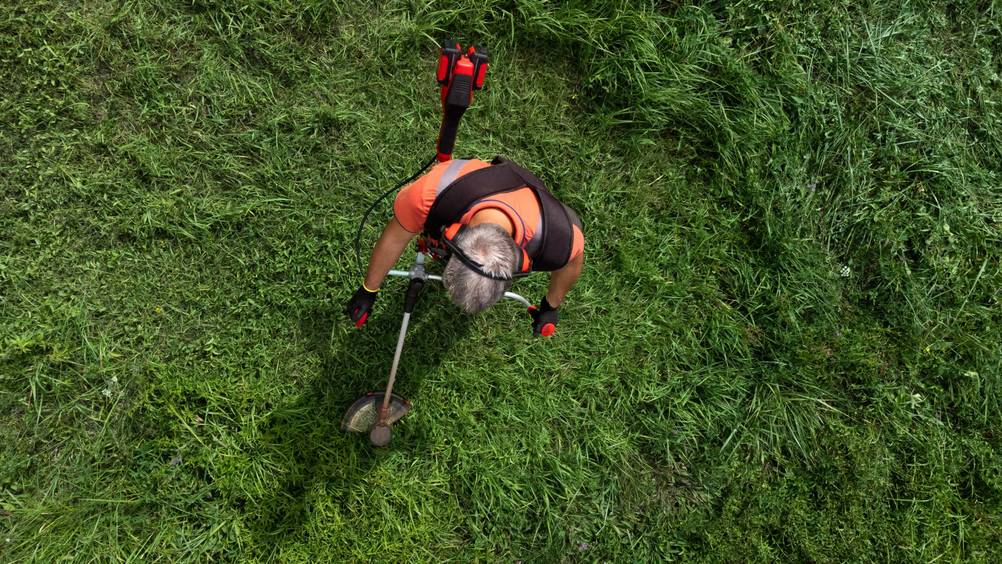 Blick von oben auf einen Mann mit Rasentrimmer.