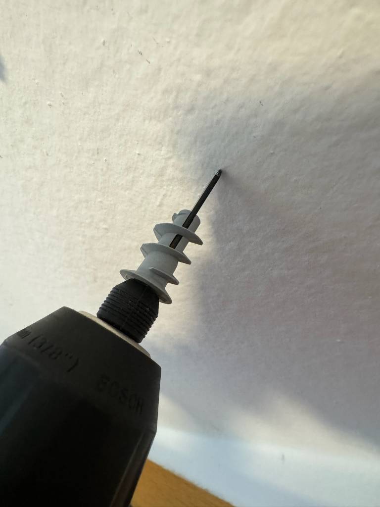 Hohlraumdübel im Test: Ein Dübel wird mit einer Maschine eingedreht.