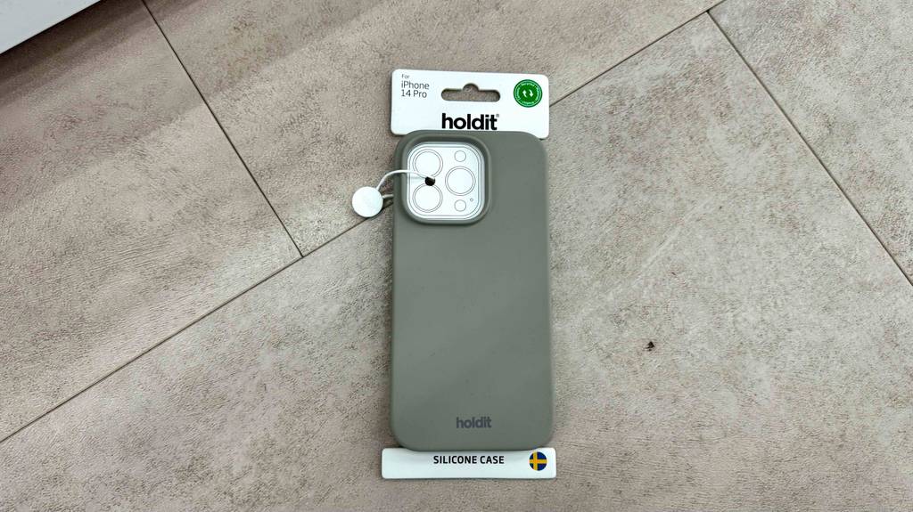 Eine getestete iPhone-14-Pro-Hülle in Grau liegt auf einem grauen Steinboden.