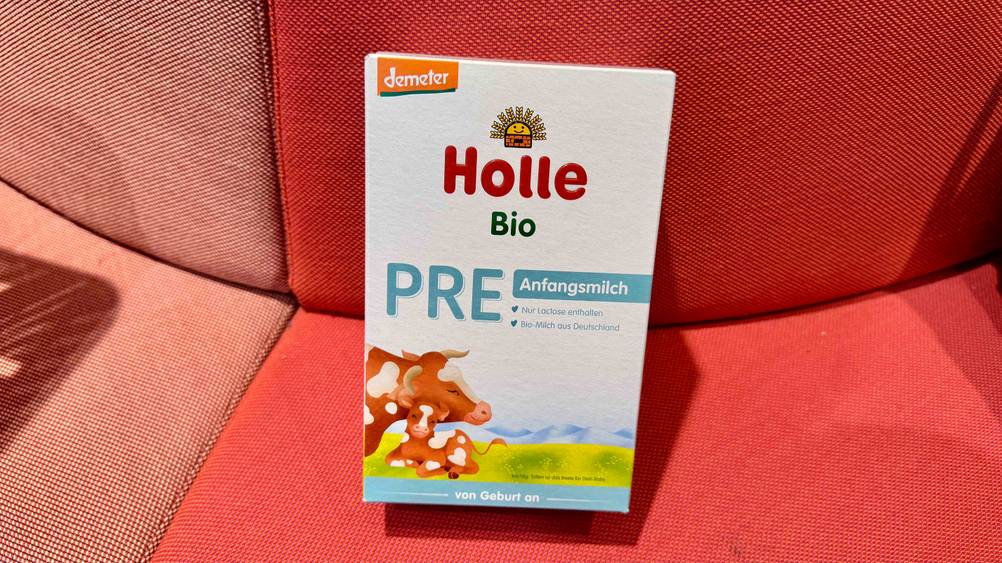 Eine Packung des getesteten Holle-Milchpulvers auf einem roten Polster.